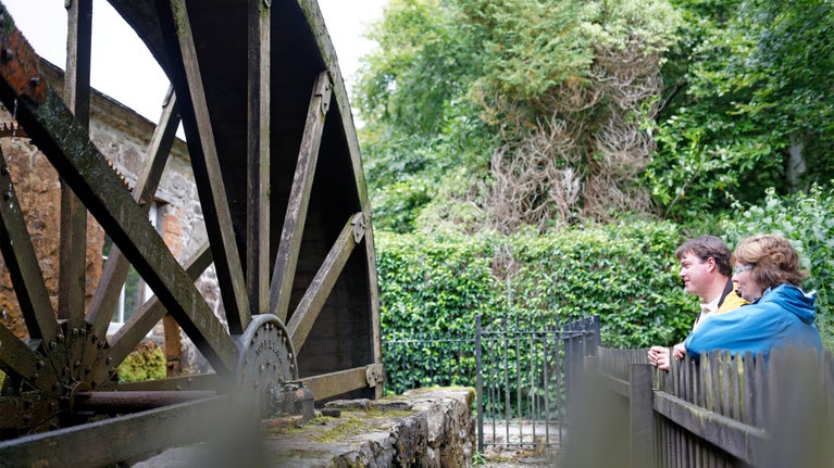 Visitors looking at a water mill, in the grounds of Florence Court, County Fermanagh